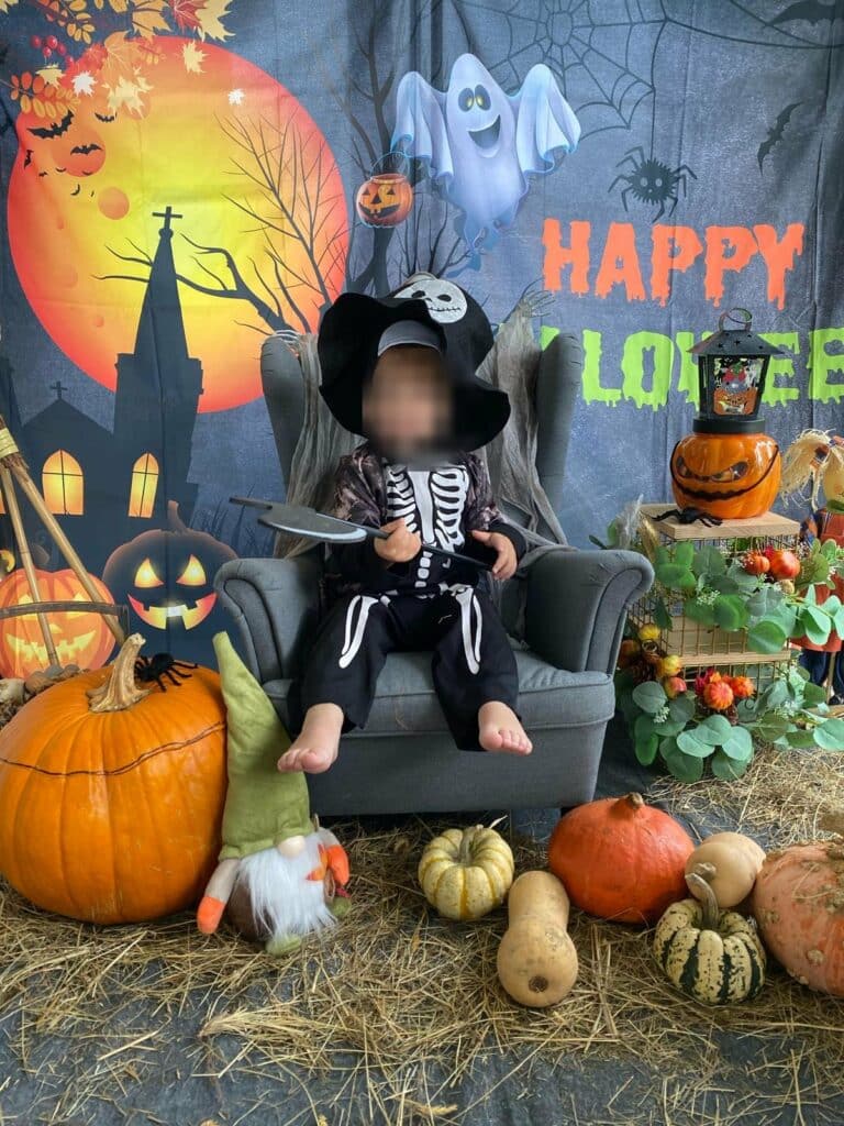 Enfant déguisé en squelette pour Halloween, entouré de citrouilles